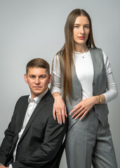 Beautiful young couple. Guy sits on chair, the girl leans on his back. Dressed in stylish modern clothes. Studio portrait. Fashion and relationship concept