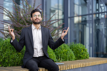 A businessman in a suit meditates outdoors, embodying mindfulness and work-life balance amidst...