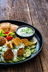 Fried meatballs with tzatziki sauce and pita bread on wooden table. Greek style food