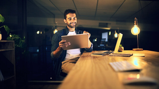 Night, typing and man in office, tablet and smile with graphic designer, internet and online reading. Person, evening and employee in workplace, tech and app for creative project and social media