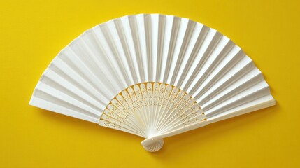 Ultra quality image of white hand fan arranged flat on a yellow background, viewed from above.
