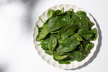 Fresh spinach leaves in bowl on white background for healthy eating