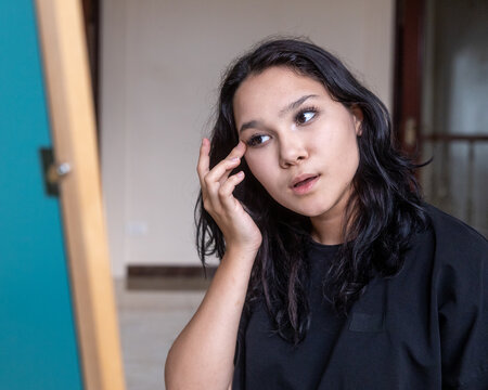 Asian girl examining reflection in mirror
