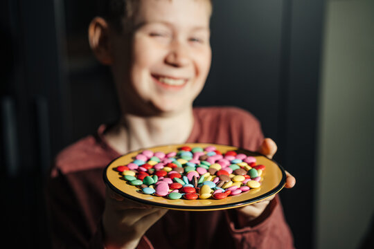 Child holding a plate of colorful candy at home