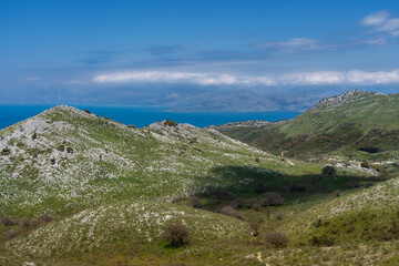 Naklejka premium Scenic mountain and coastal landscape with green hills and stunning sea view under a clear blue sky — perfect nature background for hiking, travel, and adventure photography