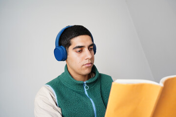 Young man reading with headphones in quiet setting
