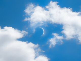 New moon in the daytime isolated. Moon in the blue sky among the clouds. Celestial landscape.