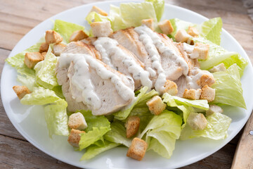 Crunchy Caesar salad with chicken on wooden table