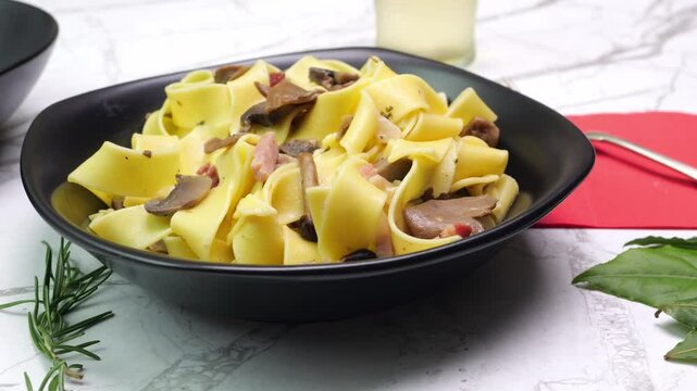 Primo piano di un piatto con pappardelle ai funghi e pancetta