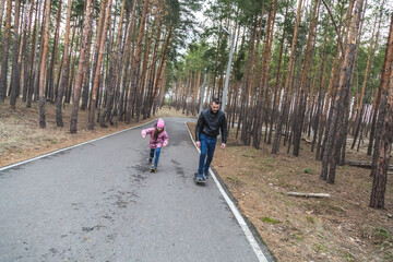 Obraz premium Father and daughter riding skateboards in the forest.