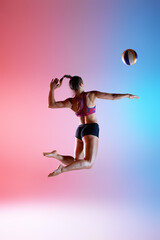 Photo in motion, rear view of jumping athlete with extended arm targeting volleyball in neon...
