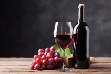 Fototapeta premium Glass of red wine and bottle on wooden table