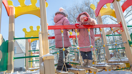 Two little girl playing on the playground on a winter day
