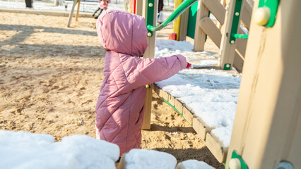 Grandfather playing with his granddaughter on the playground in the park in winter