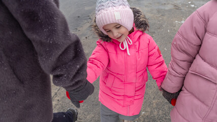 Grandmother and girls walk along a snowy street in winter