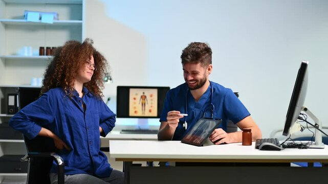 Doctor explains spinal X-ray on tablet to patient with lower back pain. Concept of orthopedic care, diagnosis, posture issues