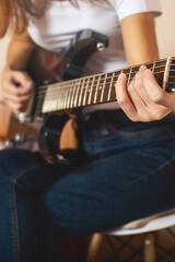 Close-up of girl's hands playing electric guitar indoors