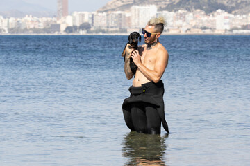 Man on the beach holding his dog.