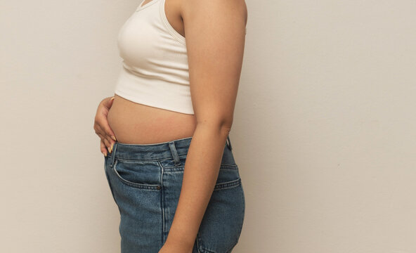 Woman touching stomach while wearing jeans
