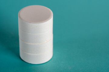 Four white medicine tablets laying on side as staple isolated on blue pastel background as macro 1