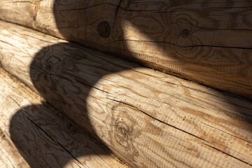 Close-up of a wooden log wall surface with sunlight