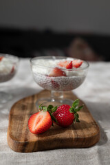 Healthy homemade chia dessert with strawberry and coconut on sunny cozy background 