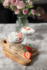 Healthy homemade chia dessert with strawberry and coconut on sunny cozy background 