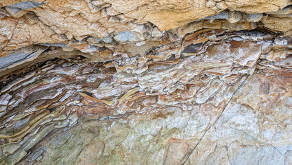 Colorful rock surface displaying layered geological strata, revealing intricate textures and...