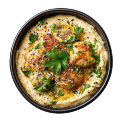 Creamy hummus topped with browned chicken pieces, garnished with fresh parsley, in a dark bowl