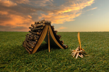 Book-shaped tent with twig walls and campfire at sunset. Creative photo showing literature as adventure. Concept of outdoor stories, imagination, freedom, education, and fantasy.