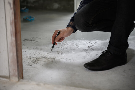 Engineer or inspector examining cracked concrete floor during house construction. Quality control, building inspection, structural defect, or real estate maintenance concept.