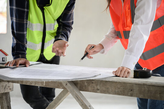 Female civil engineer with personal safety equipment check and consult with construction site foreman technician for inspect building construct process during follow up process. Engineering concept.