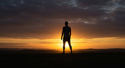 Obraz premium Runner’s Silhouette Against Dramatic Sunset on Hilltop