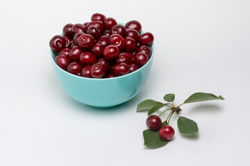 Ripe dark red cherries in blue bowl isolated on white background. Different angles. Place for design.  Close-up.