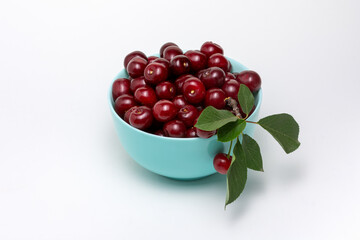 Ripe dark red cherries in blue bowl isolated on white background. Different angles. Place for design.  Close-up.