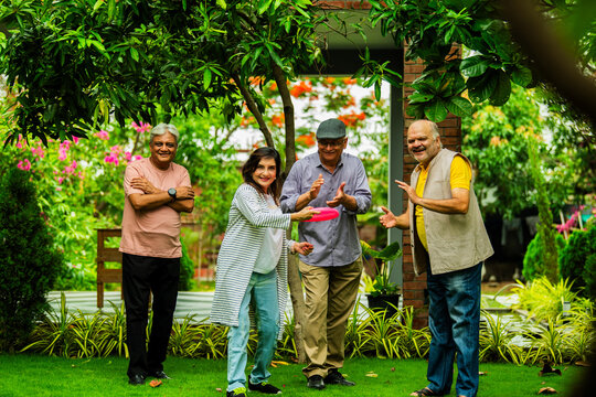Elderly Indian friends playing frisbee and having fun during outdoor garden meetup