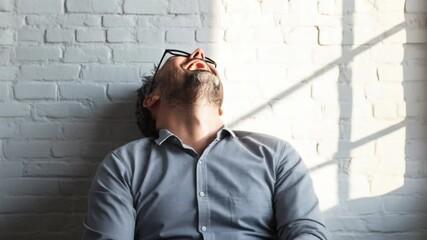 Cheerful man expressing joy with laughter and positive emotion against brick wall