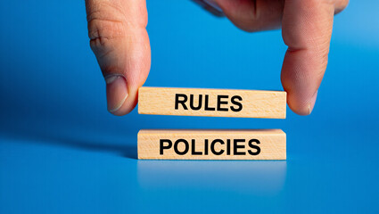 Hand arranging wooden blocks spelling rules and policies