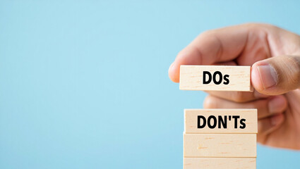 Hand placing wooden block with dos above donts stack