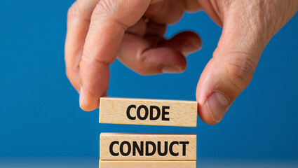 Hand placing wooden blocks spelling code conduct ethics business concept