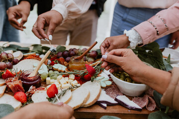 hands and Outdoor charcuterie board with wine and cheese on wood table outdoors