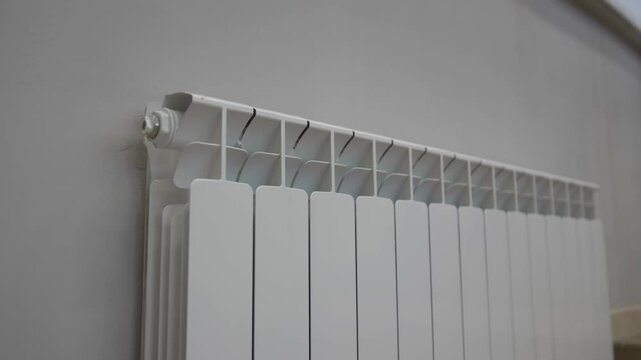 Bimetallic radiator mounted on smooth pale wall blends into modern educational interior. Sleek linear structure enhances warm environment
