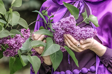 A beautiful young woman with red hair, against a background of blooming lilacs, in a cloak and hood. Medieval fantasy costume. Fairy tale heroine, princess, duchess. © Светлана 