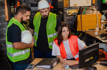 Two males workers and one woman worker at industry or factory office wearing safety gear and using...