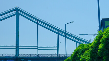 Fototapeta premium Minimalist pedestrian bridge underframe photographed from below in urban setting.