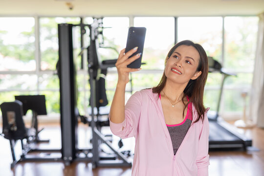 portrait of a woman using phone in gym taking selfie - Powered by Adobe