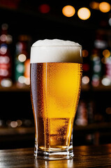 A glass of light beer on the bar counter in a bar. No people.