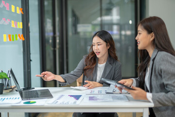 Two businesswoman hands or accountants working together on financial investment on calculator, calculating, analyzing business growth and marketing on graph.