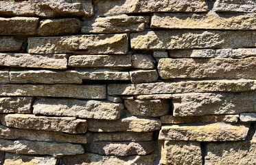 Natural stone wall texture close-up. Rough stacked sandstone masonry surface for backgrounds, architectural design, and construction details.