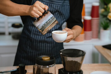 Barista pouring milk into cappuccino, creating latte art in cozy café setting, showcasing morning preparation, craftsmanship, and coffee culture indoors.